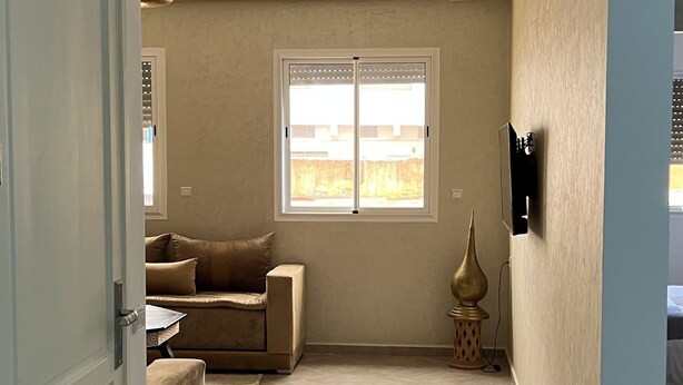 Ein Zimmer mit großem Fenster, einer Couch, einem kleinen Tisch und einer dekorativen Vase.