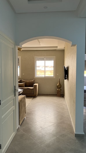 A room with a large window, a sofa, a small table, and a decorative vase.