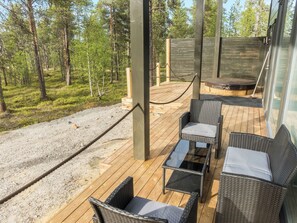 Eine Terrasse im Freien mit Korbmöbeln, einem Glastisch und einem Seilgeländer.