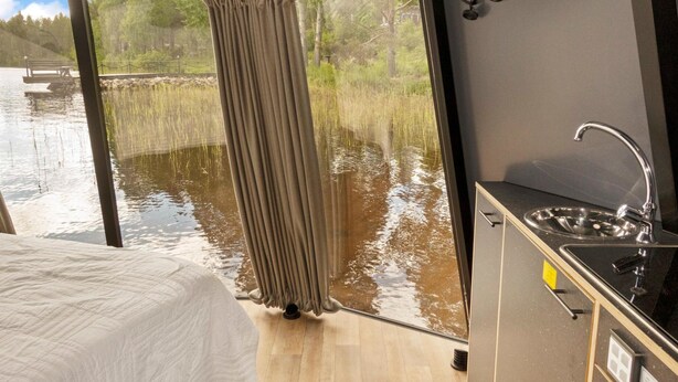 A room with a bed, a sink, and a view of a body of water through a window. - Lystikämän elämys by Interhome (Rovaniemi)