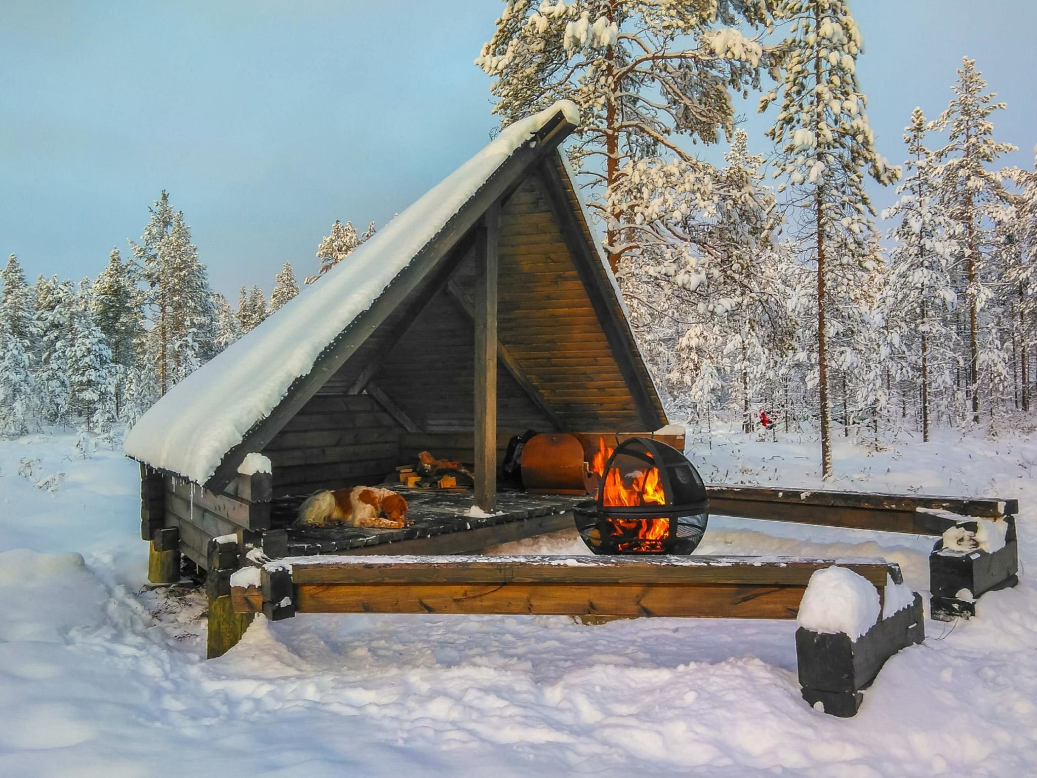 Une cabane en bois avec un toit enneigé et une cheminée.