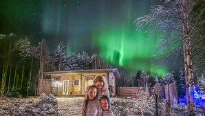 A building with a snow-covered landscape and a green aurora in the background. - Lystikämän elämys by Interhome (Rovaniemi)