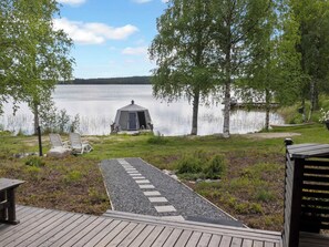Una cabaña junto al lago con un porche, rodeada de árboles y vistas despejadas al lago.