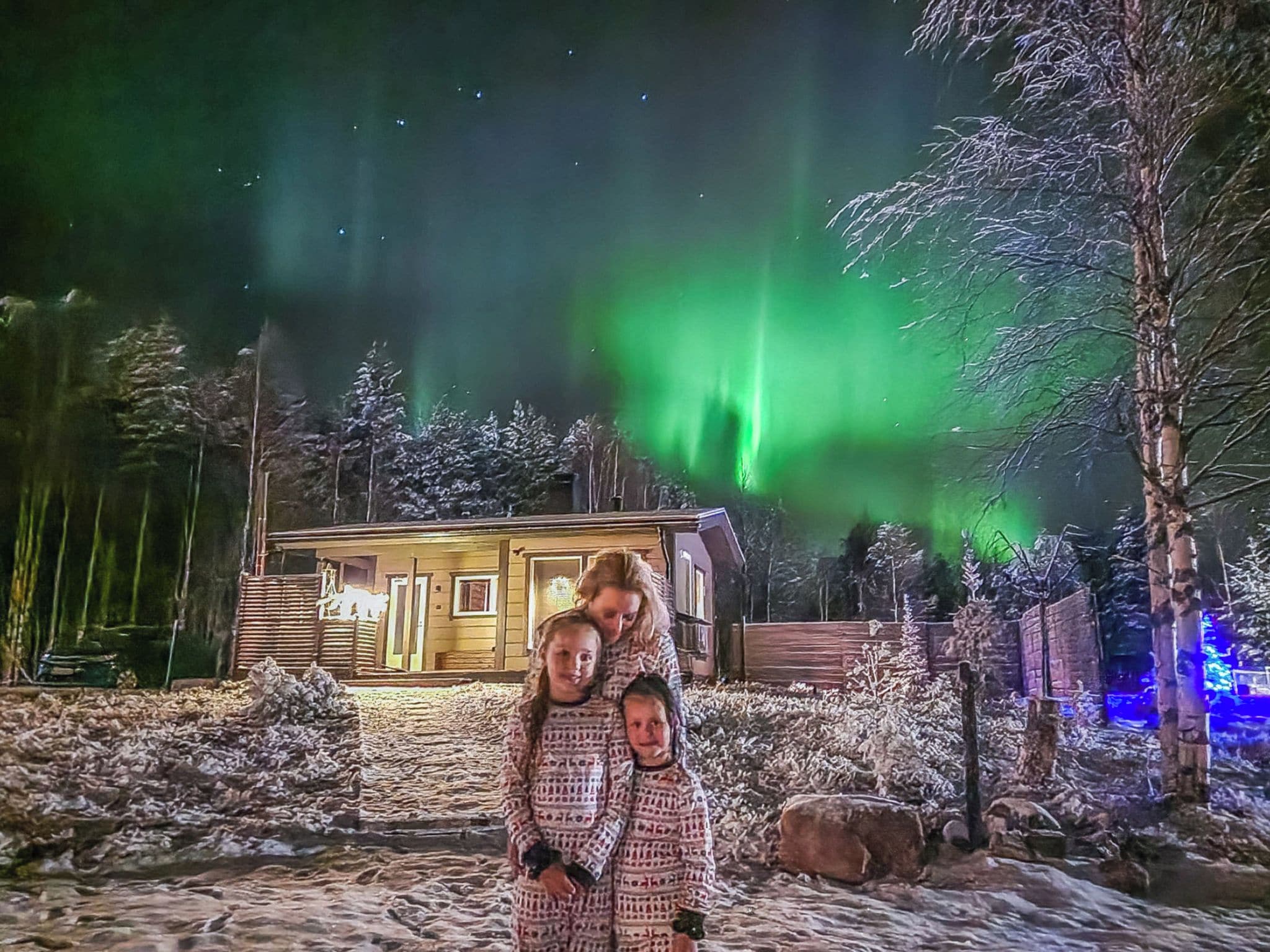 Een blokhut met een sneeuwbedekt landschap en een zichtbare poollichtshow op de achtergrond.