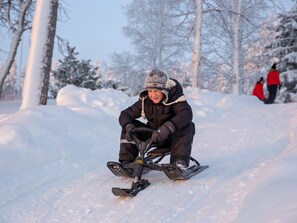 Une personne sur une luge, dans un décor enneigé en plein air.