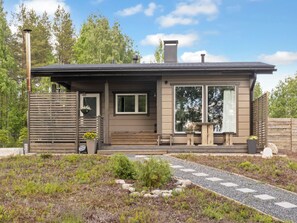 Een modern gelijkvloers huis met een overdekte veranda, grote ramen en een pad van stenen dat naar de ingang leidt.