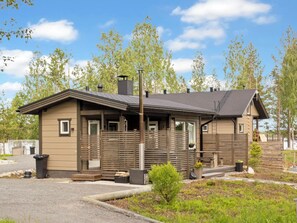 Een lodge met een overdekt terras, een open haard en een kleine tuin.