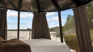 A bedroom with a large bed, a view of a lake, and curtains. - Lystikämän elämys by Interhome (Rovaniemi)