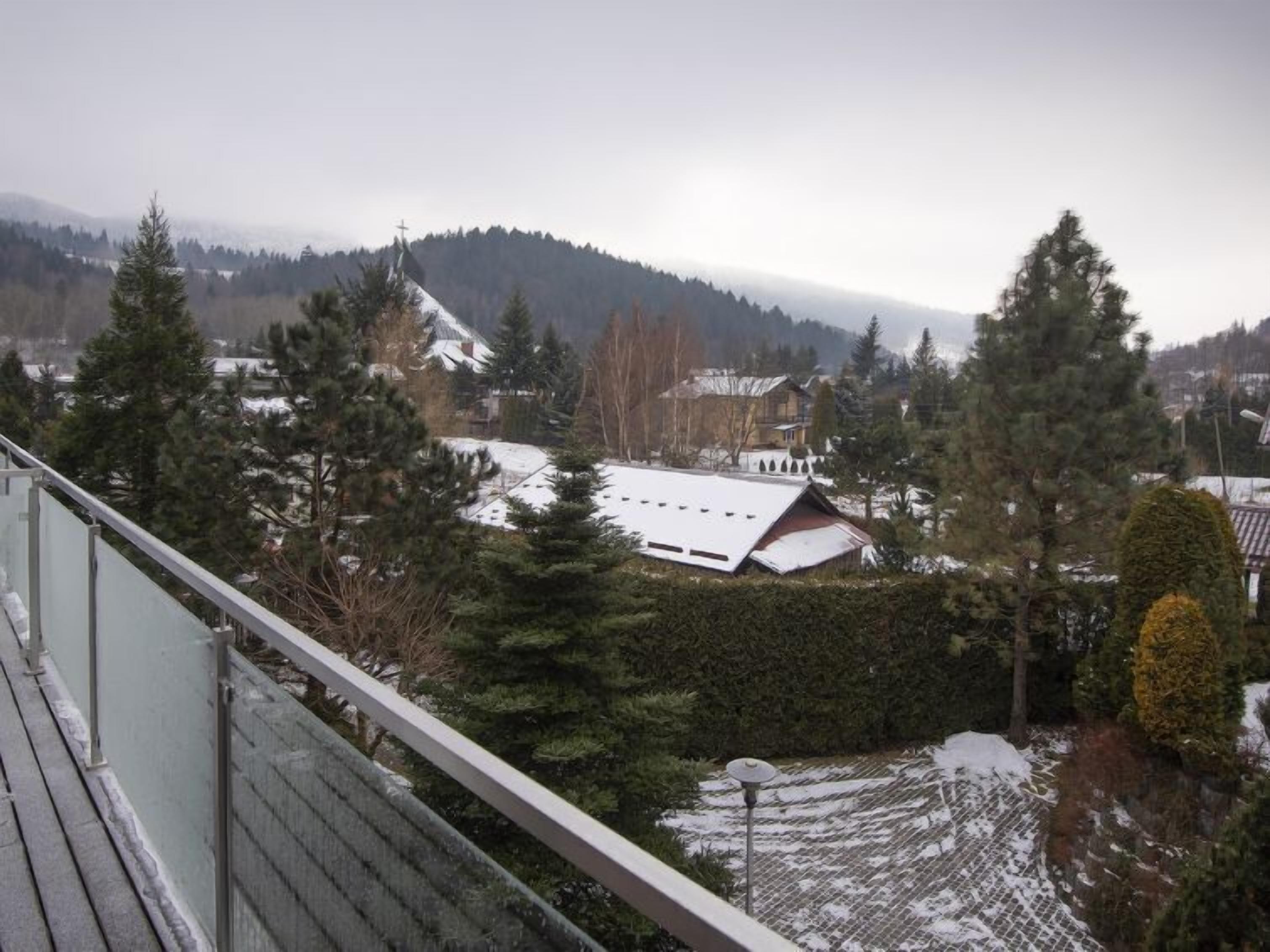 Eine verschneite Landschaft mit einem Haus und Bäumen.