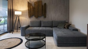 Ein modernes Wohnzimmer mit einem grauen Ecksofa, einem runden Couchtisch und einer Stehlampe.