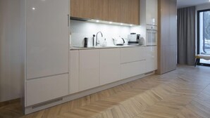 Eine moderne Küche mit weißen Schränken, einem hölzernen oberen Regal und einem eingebauten Backofen.