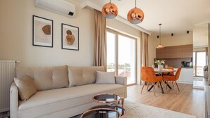 En moderne stue med sofa, sofabord og spiseplads med orange stole.