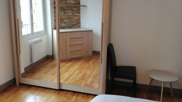 A room with a sliding wardrobe, a small table, and a chair.
