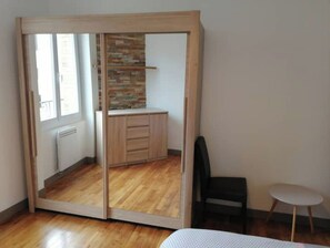 Una habitación con armario corredero, una mesita y una silla.