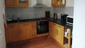A kitchen with wooden cabinets, a gas stove, a microwave, and a built-in oven.