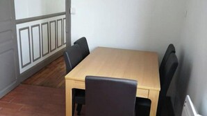 A small dining area with a wooden table and four chairs, a radiator, and a sliding glass door leading to a balcony.