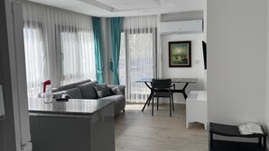 Ein modernes Wohnzimmer mit grauem Sofa, einem Esstisch und einer Küchenzeile mit grauer Arbeitsplatte.