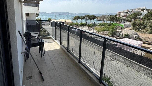 Ein Balkon mit Meerblick, einem Stuhl, einem Tisch und einem Geländer.
