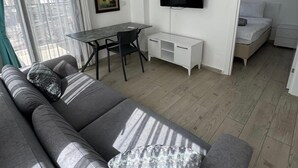 Ein modernes Wohnzimmer mit einer Couch, einem Esstisch und einem Fernseher.