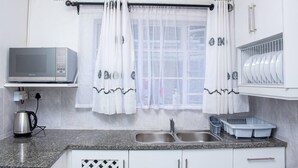 Une cuisine équipée d’un four à micro-ondes, d’une bouilloire, d’un évier et d’un égouttoir à vaisselle.