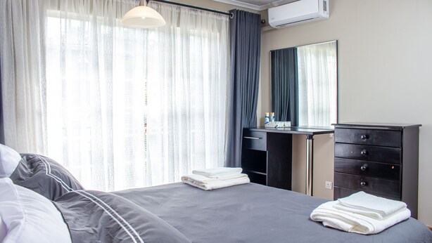 Une chambre d’hôtel avec un lit, un bureau, une commode et une fenêtre avec des rideaux.