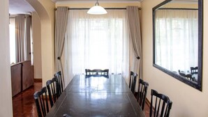 Une salle à manger avec une longue table, des chaises et un grand miroir au mur.