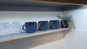 A shelf with four blue ceramic mugs and a potted plant. - Lopez Home Crawley (Crawley)