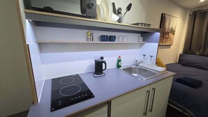 A compact kitchenette with an induction cooktop, a sink, and a small countertop. - Lopez Home Crawley (Crawley)