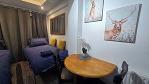 A bedroom with two beds, a wooden table, and two paintings of deer. - Lopez Home Crawley (Crawley)
