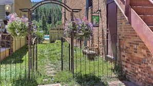Maalaishenkinen sisäänkäynti, jossa on metallinen portti, tiilestä rakennettu rakennus ja portaikko.
