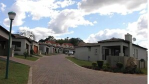 A residential street with houses, a paved road, and a street lamp. - A home away from home (Mbombela)