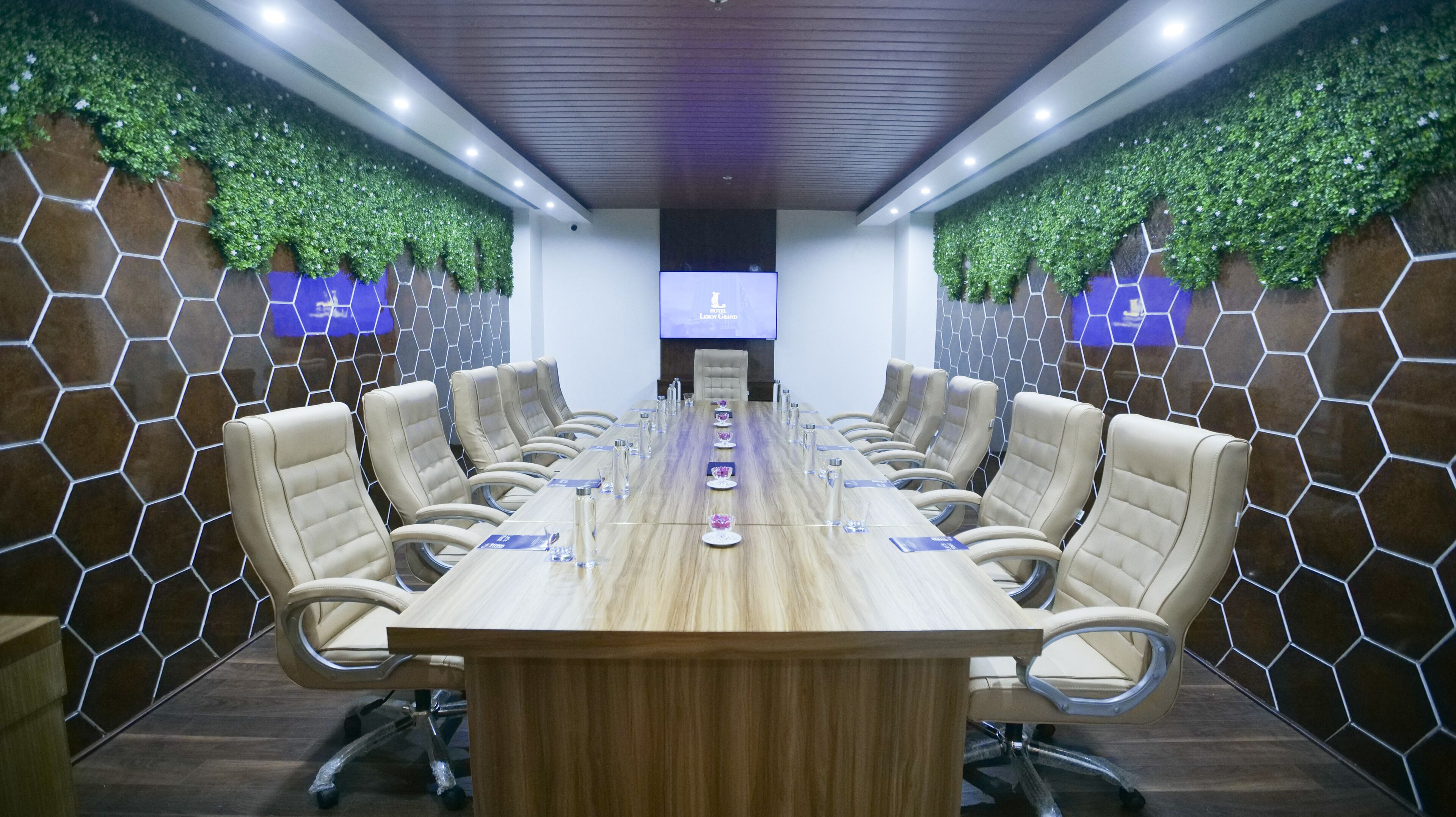 A conference room with a long table, multiple chairs, and a screen at the front.
