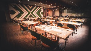 A restaurant with multiple tables and chairs, wooden flooring, and a decorative wall with geometric patterns. - Hotel Leroy Grand (Bengaluru)