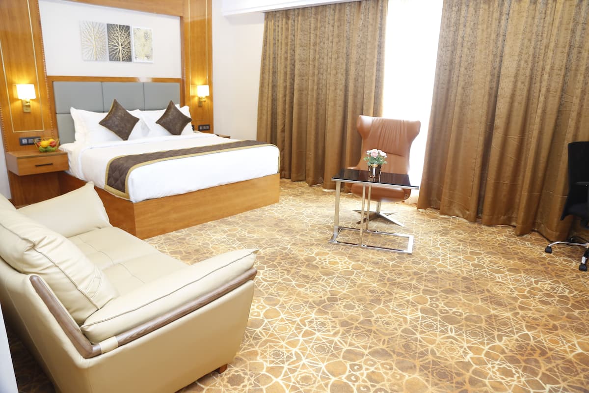 A hotel room with a bed, a sofa, a small table, and a chair.