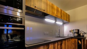 A modern kitchen with wooden cabinets, stainless steel appliances, and a black countertop.
