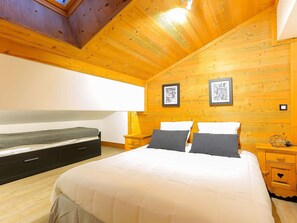 Um quarto com uma cama grande, paredes de madeira e duas imagens emolduradas na parede.