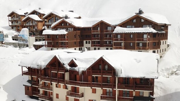 A multi-story wooden hotel with balconies, surrounded by snow.