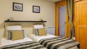 A bedroom with two beds, a wooden door, and two framed pictures on the wall.