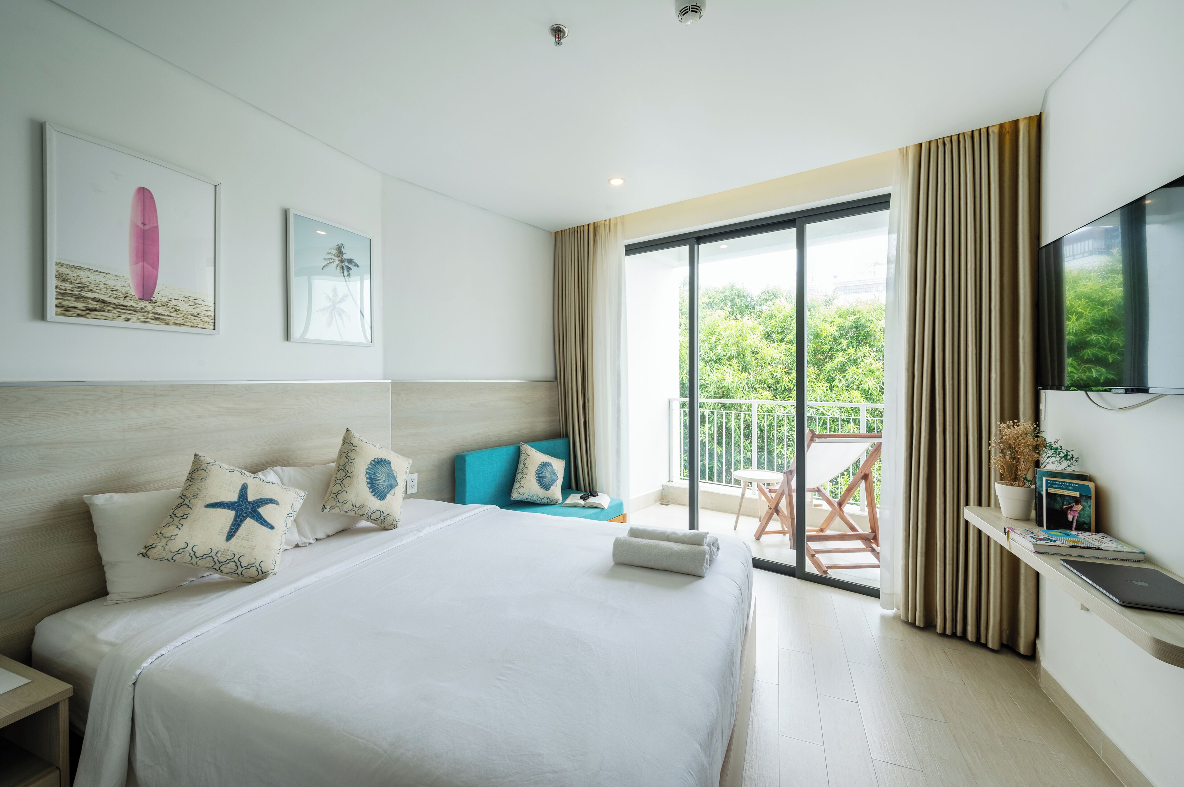 Una habitación de hotel con una cama grande, un balcón con vistas y un televisor en la pared.
