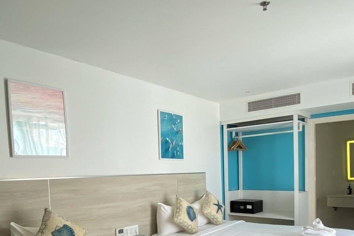 A hotel room with two beds, a desk, a wardrobe, and a bathroom.