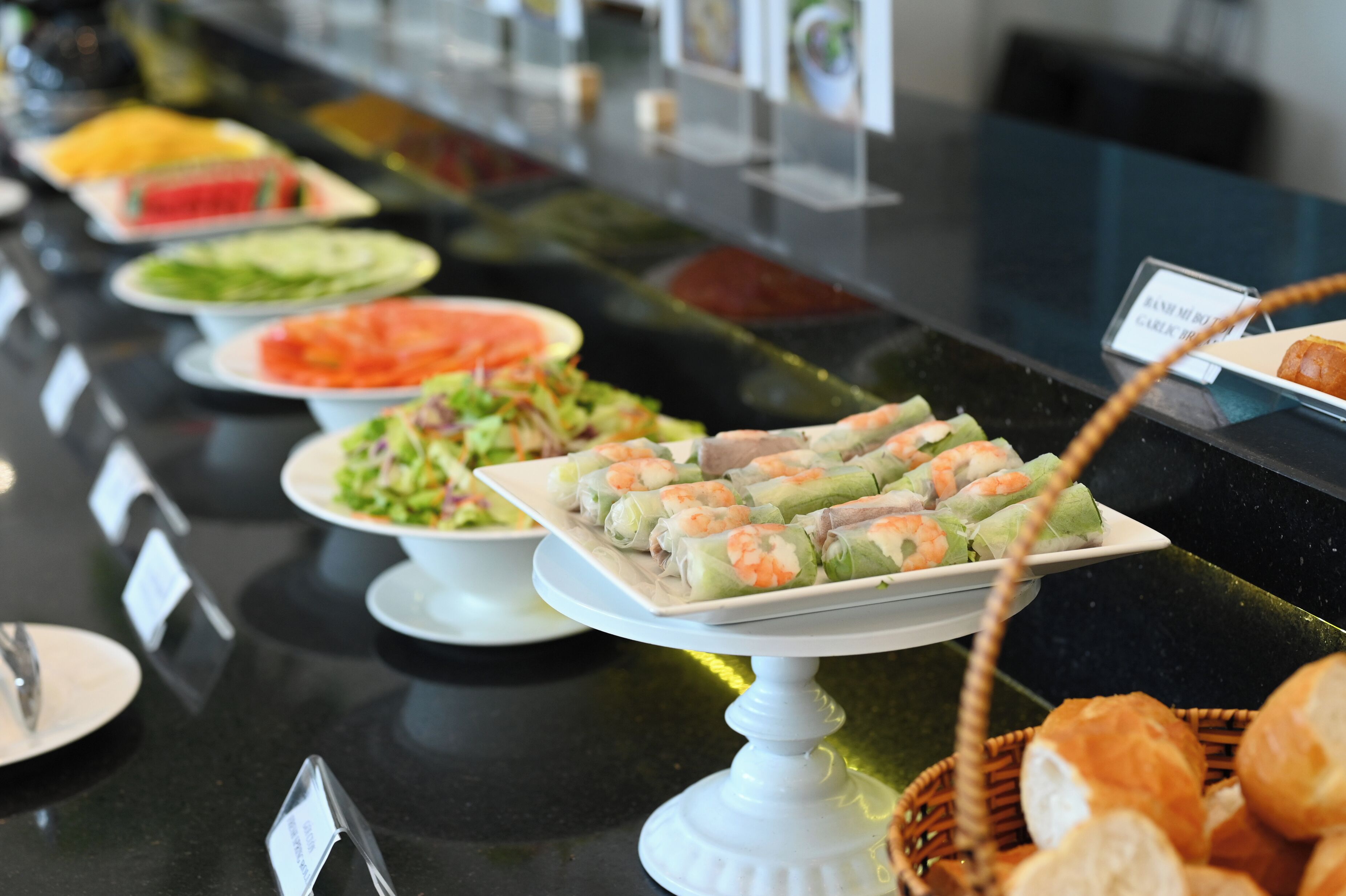 Un buffet proposant une variété de plats, notamment des salades, des légumes et des rouleaux de printemps.