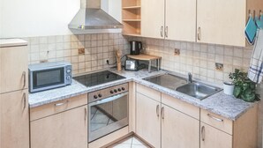 A compact kitchen with a microwave, stove, sink, and a small countertop. - Lovely apartment in Barth with WiFi (Barth)