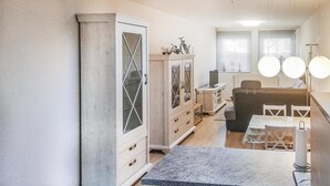 A modern kitchen with a marble countertop, a built-in cabinet with glass doors, and a dining area with a table and chairs. - Lovely apartment in Barth with WiFi (Barth)