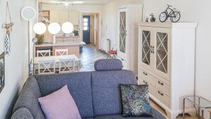 A living room with a grey sofa, a patterned cushion, a white cabinet with glass doors, and a bicycle on top. - Lovely apartment in Barth with WiFi (Barth)