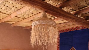 Una stanza con un letto, una lampada a sospensione, tende a motivi e un arazzo decorativo.