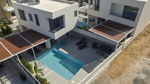 Moderni, useita kerroksia sisältävä talo, jossa on kattouima-allas, ulkotila oleskelua varten ja kiviverhoiltu julkisivu.