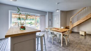 Een moderne keuken met een houten keukeneiland, witte stoelen en een trap.
