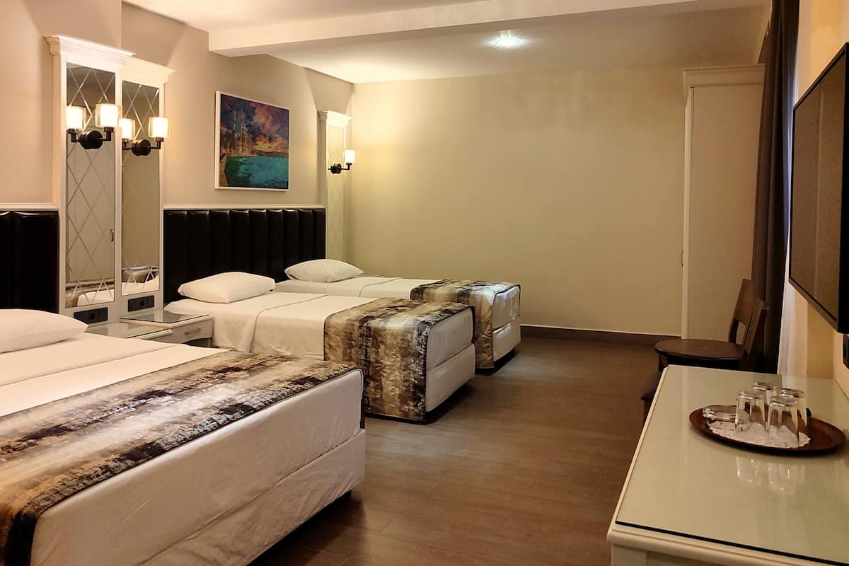 A hotel room with two beds, a large mirror, a painting, a flat-screen TV, and a tray with glasses.