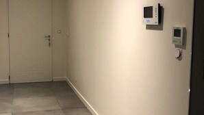 Un pasillo con una puerta cerrada, un termostato y un panel de seguridad en la pared.