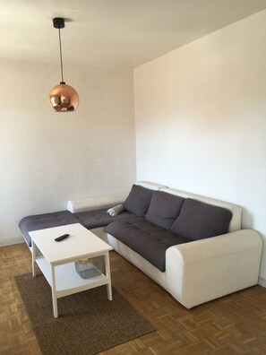 En moderne stue med en hvid sofa, et lille hvidt bord og en brun måtte.